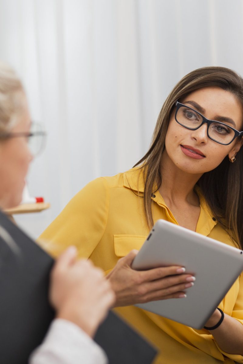 beautiful-woman-holding-tablet-looking-her-colleague