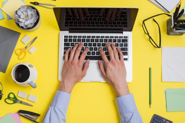 close-up-person-typing-laptop-creative-minimal-office-desk