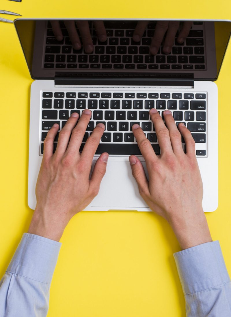 close-up-person-typing-laptop-creative-minimal-office-desk