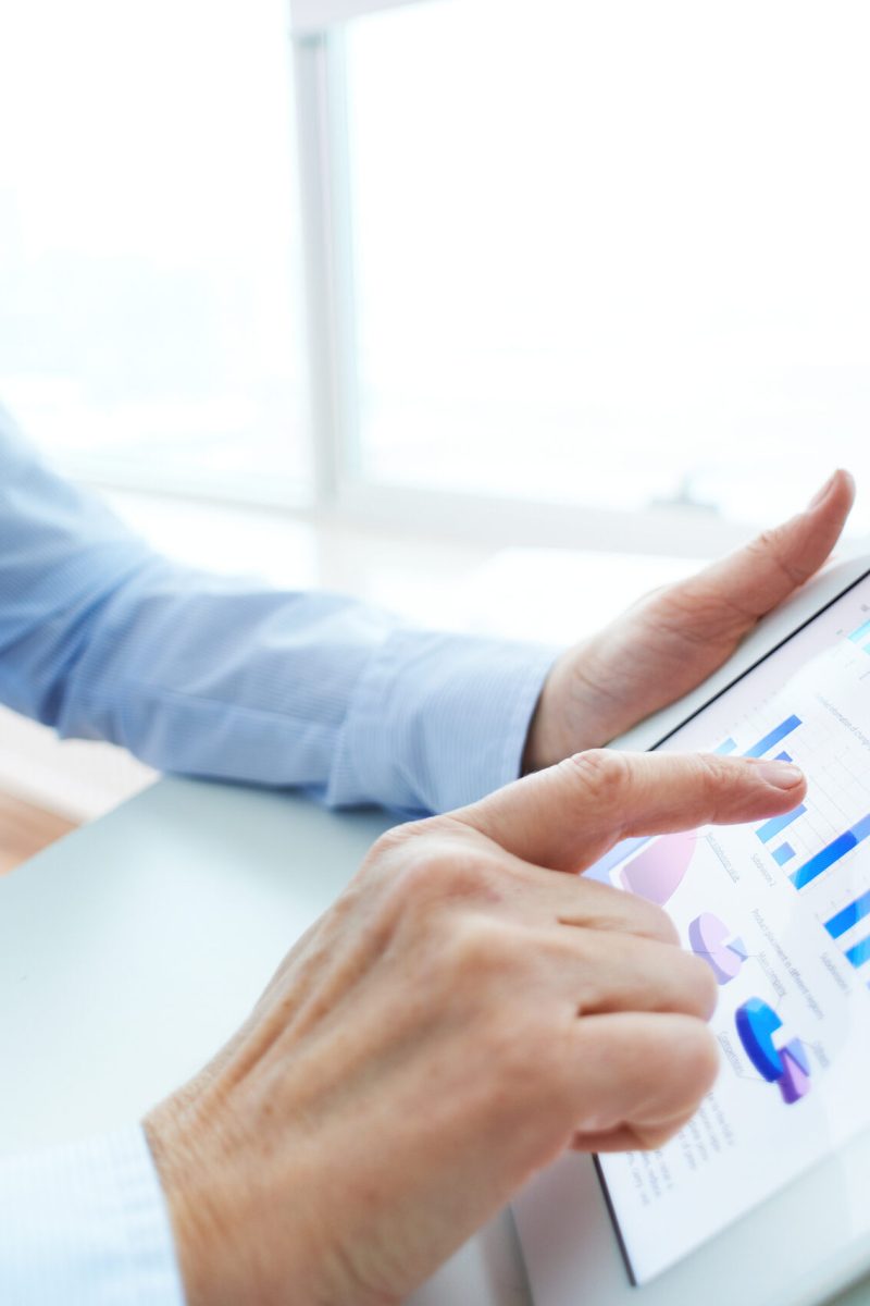 Image of human hand pointing at touchscreen with business document