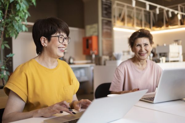 senior-women-spending-time-together-cafe-working-their-laptops